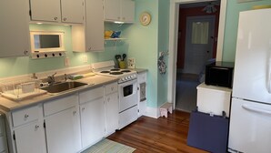 Une cuisine avec des meubles blancs, une cuisinière, un évier et un four à micro-ondes.