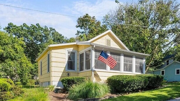 Une maison de plain-pied avec un toit à pignon, un porche à l’avant et un petit jardin devant.
