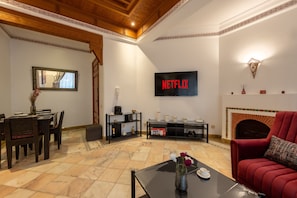 Una sala de estar con chimenea, un televisor montado en la pared y un comedor con mesa y sillas.