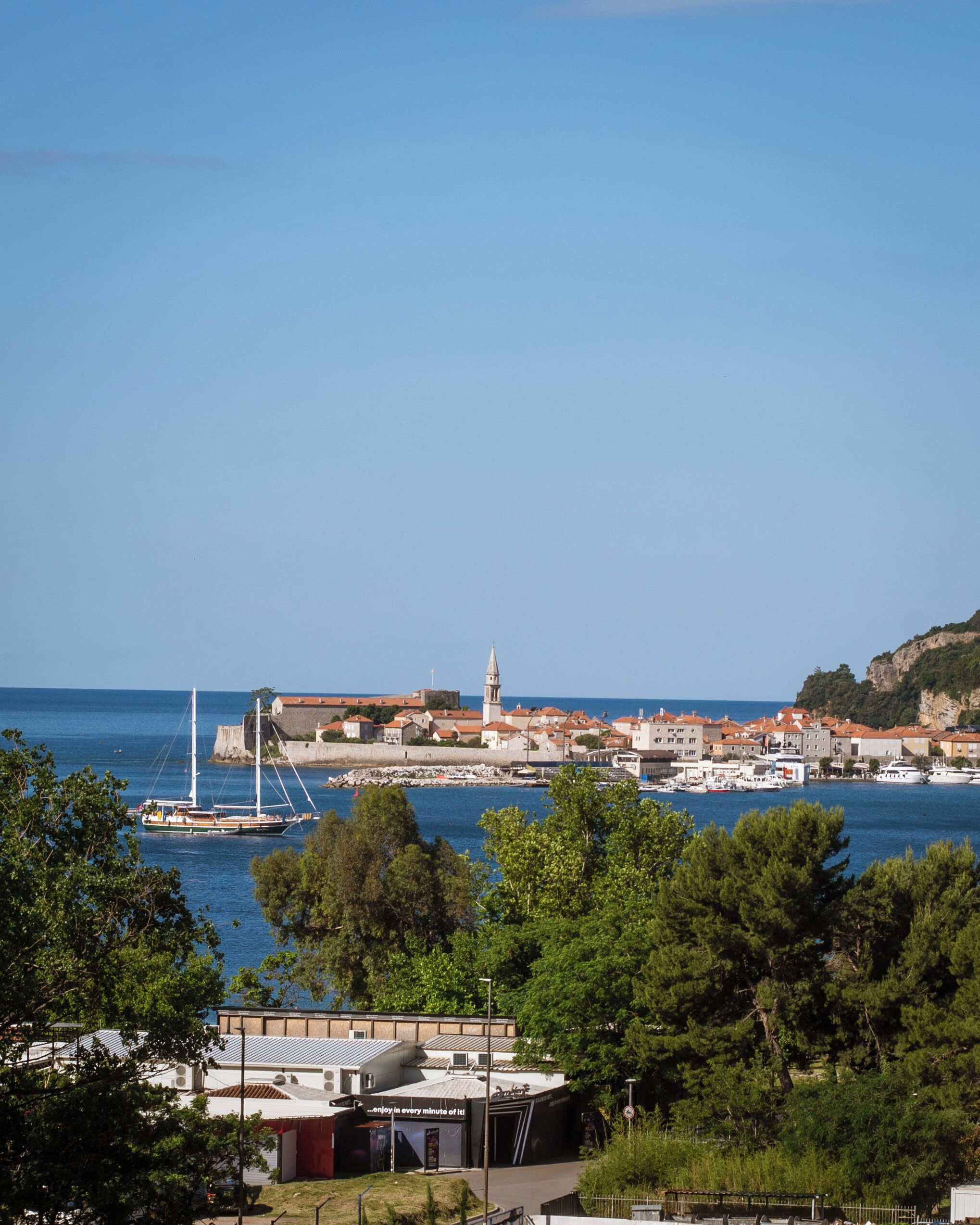 A coastal town with a prominent tower, boats docked along the harbor, and a mix of residential and commercial buildings.
