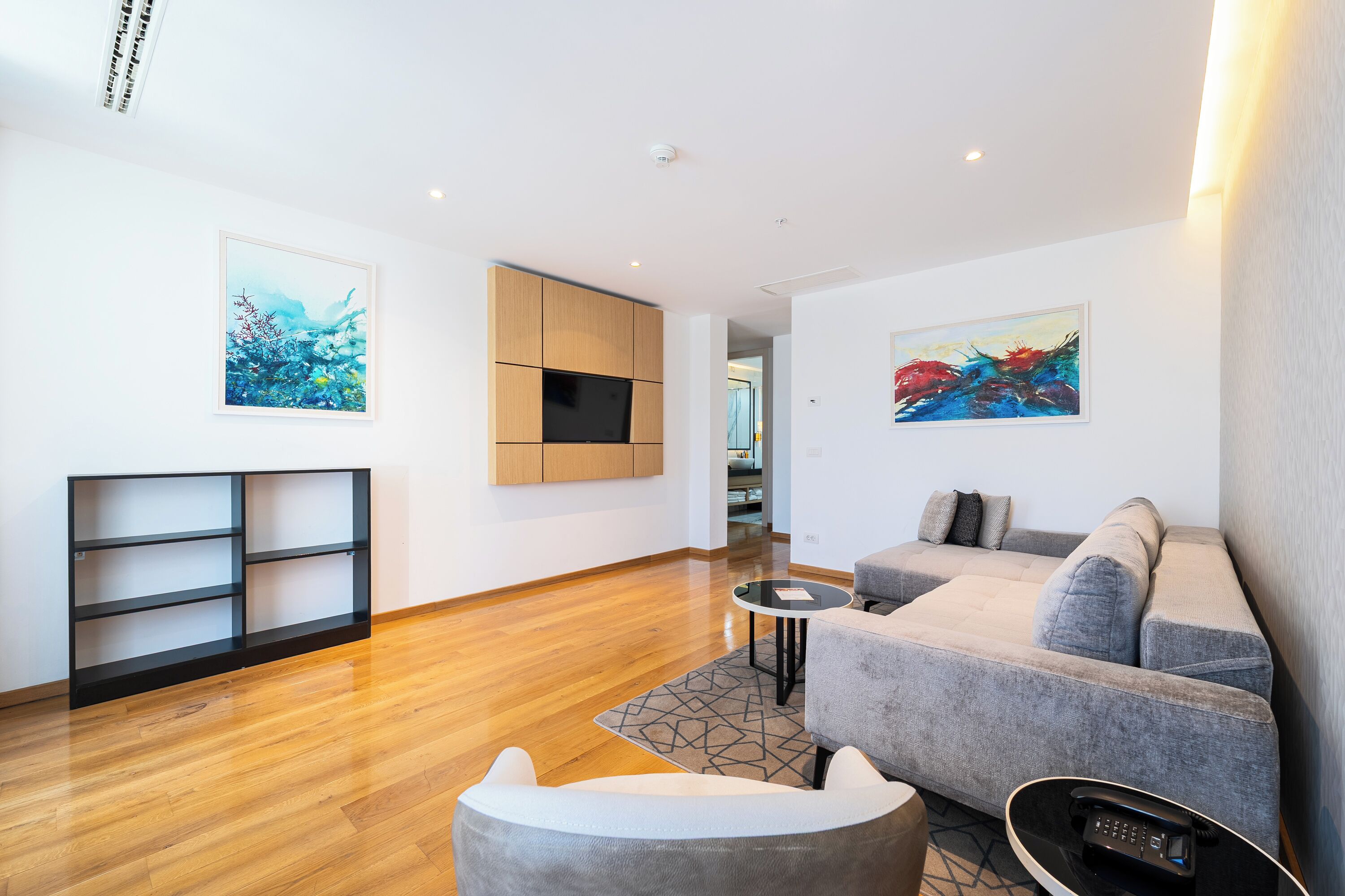 Uma sala de estar moderna com um sofá, uma mesa de centro e uma TV fixada na parede.