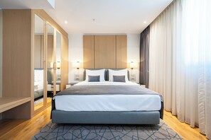 A modern hotel room with a large bed, wooden wardrobe, and a view of the city.