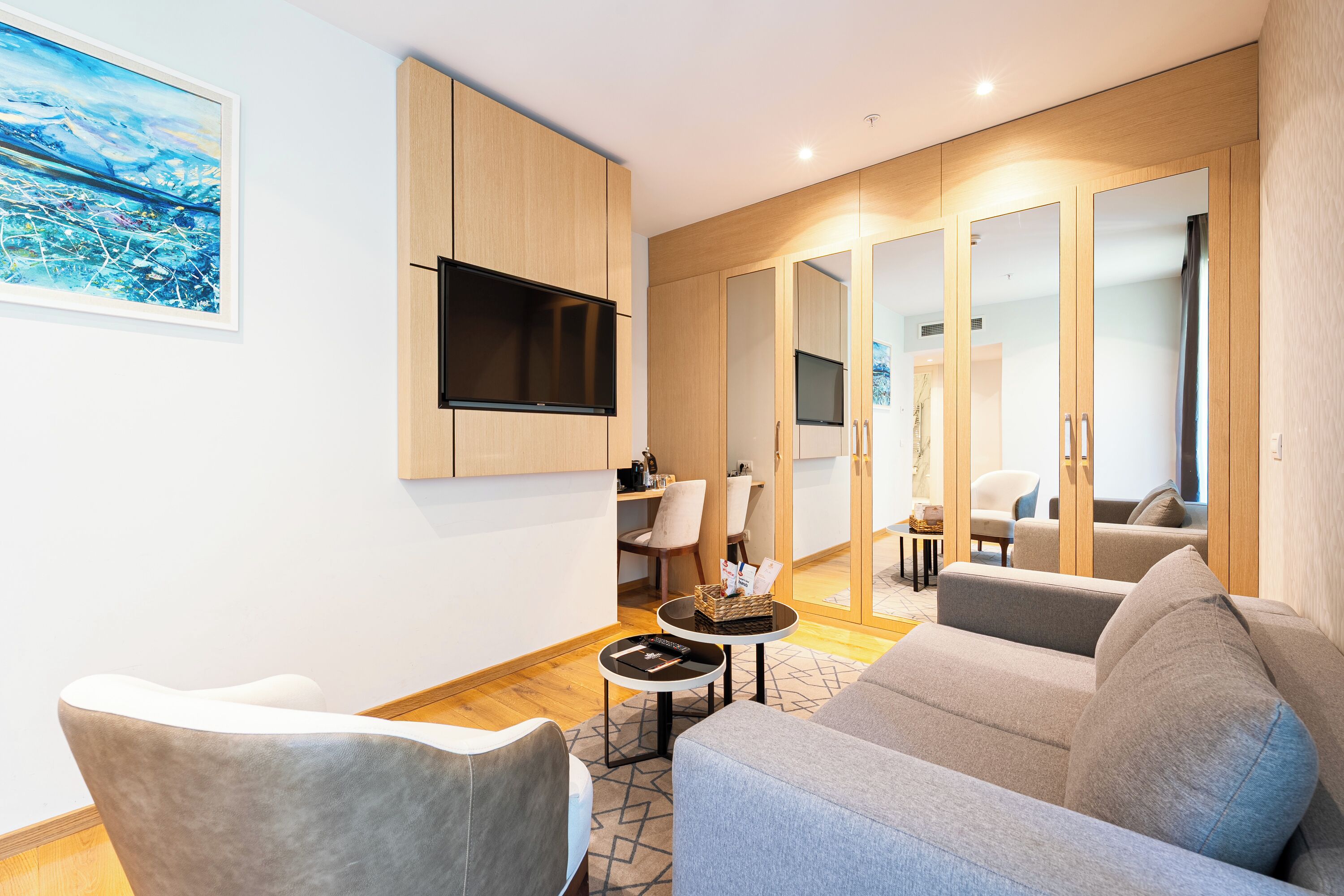 Un salon moderne comprenant un canapé, des fauteuils, un téléviseur fixé au mur et un coin repas avec une table et des chaises.