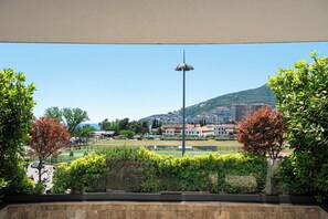 A view of a landscaped area with a street lamp, trees, and a distant cityscape.