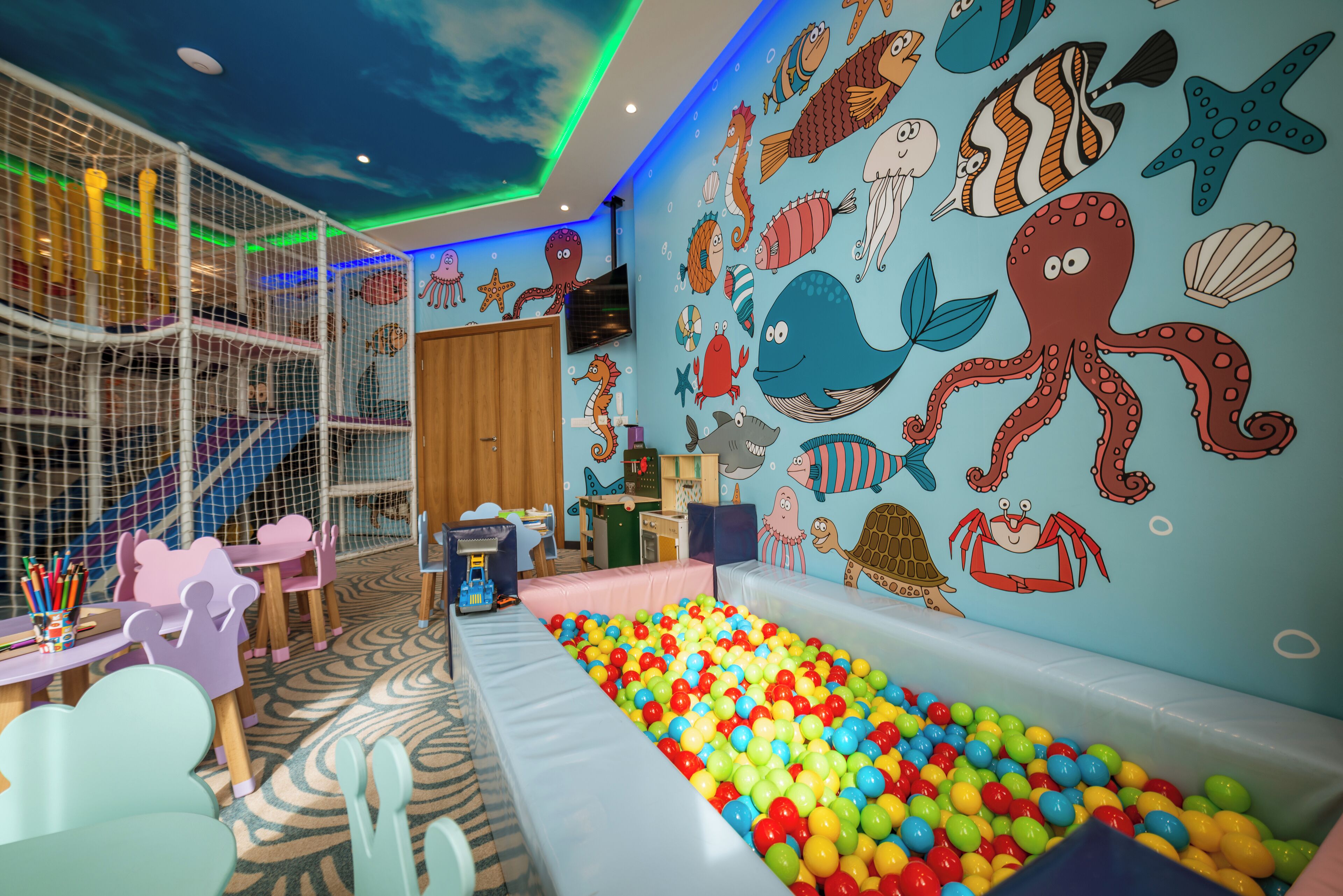 A children's play area with a ball pit, colorful wall murals, and a play structure.
