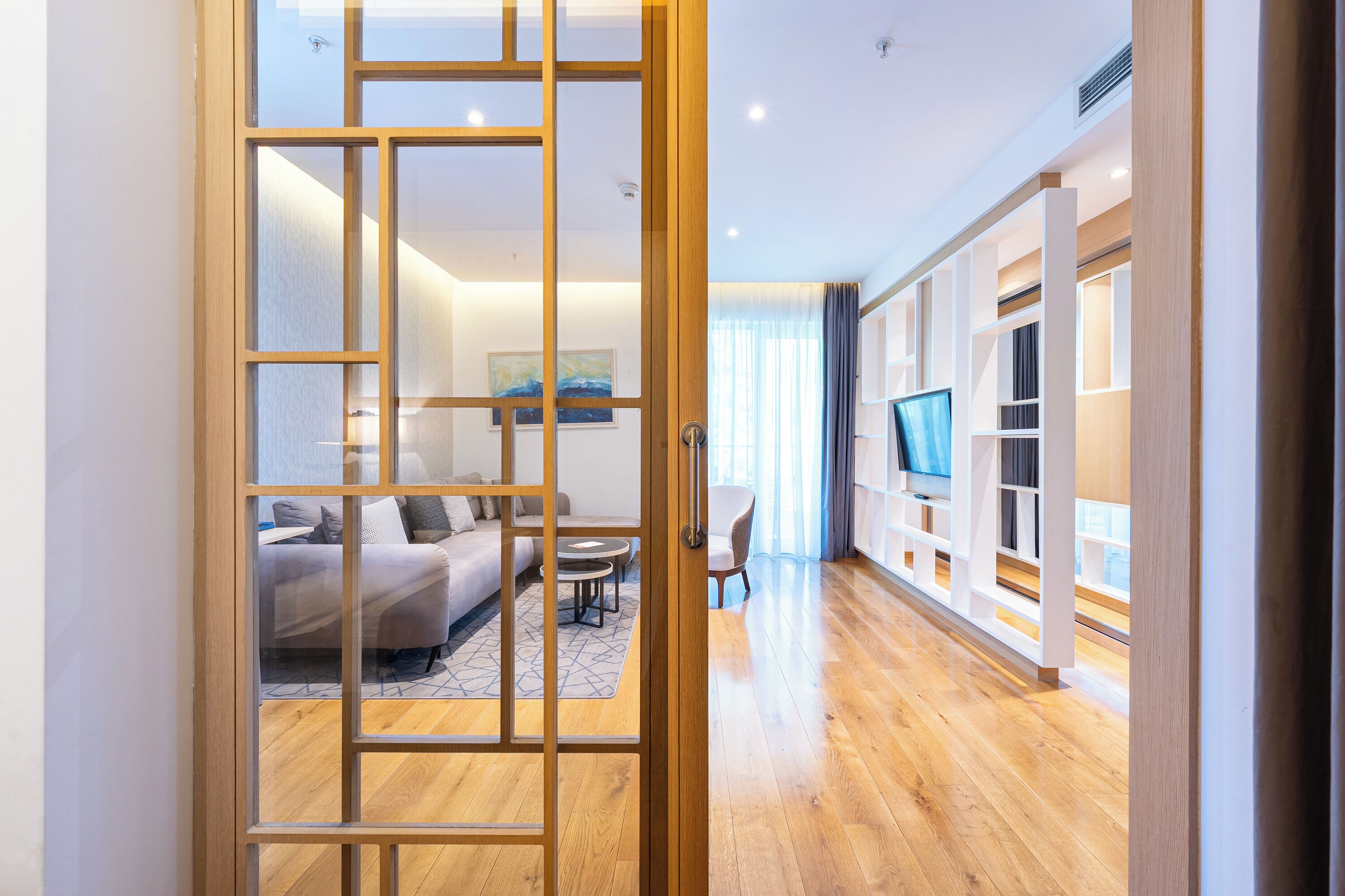 Un salon moderne avec un plancher en bois, un canapé, une table basse et un téléviseur.