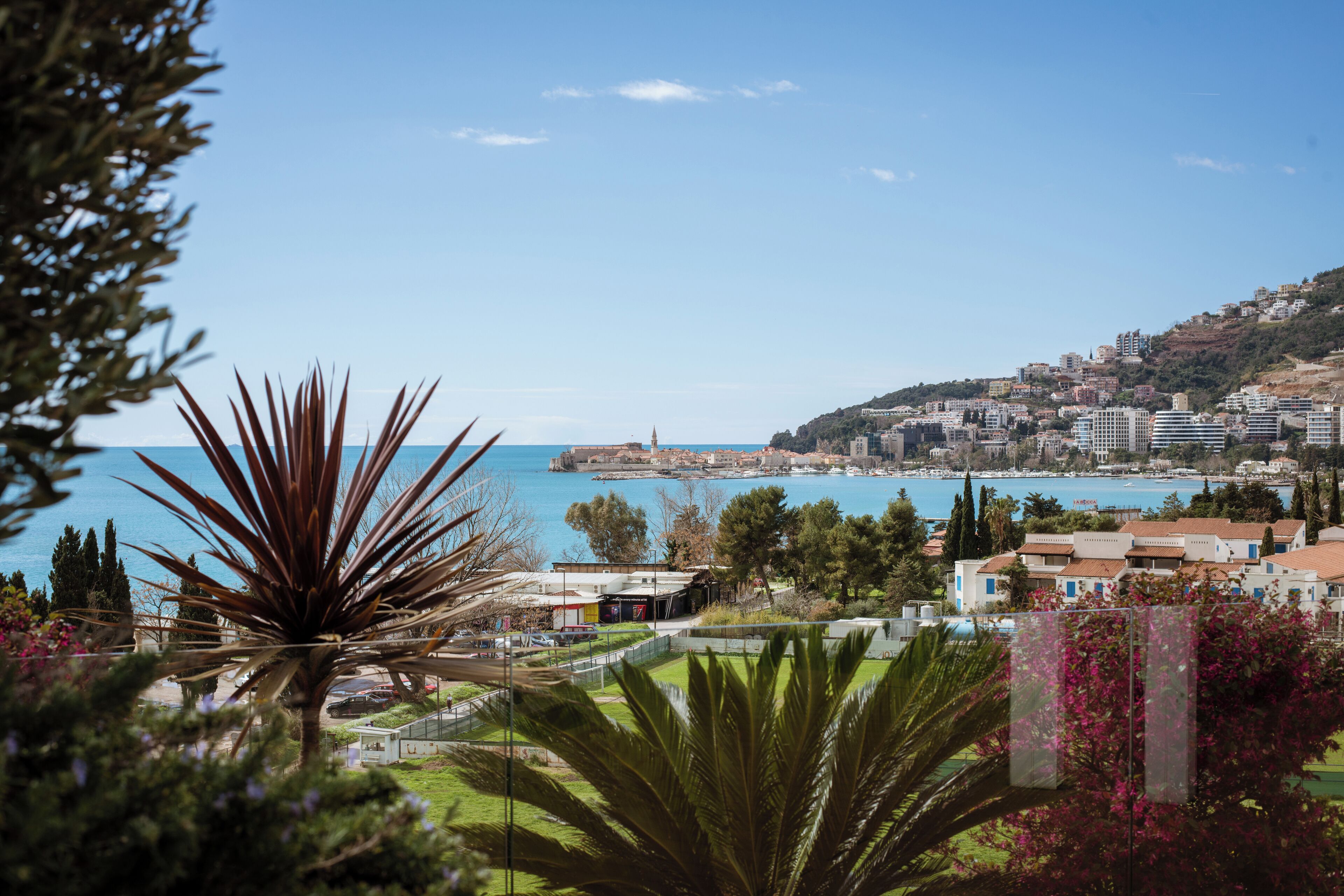 Un paisaje urbano costero con edificios, cielo despejado y vista al mar.