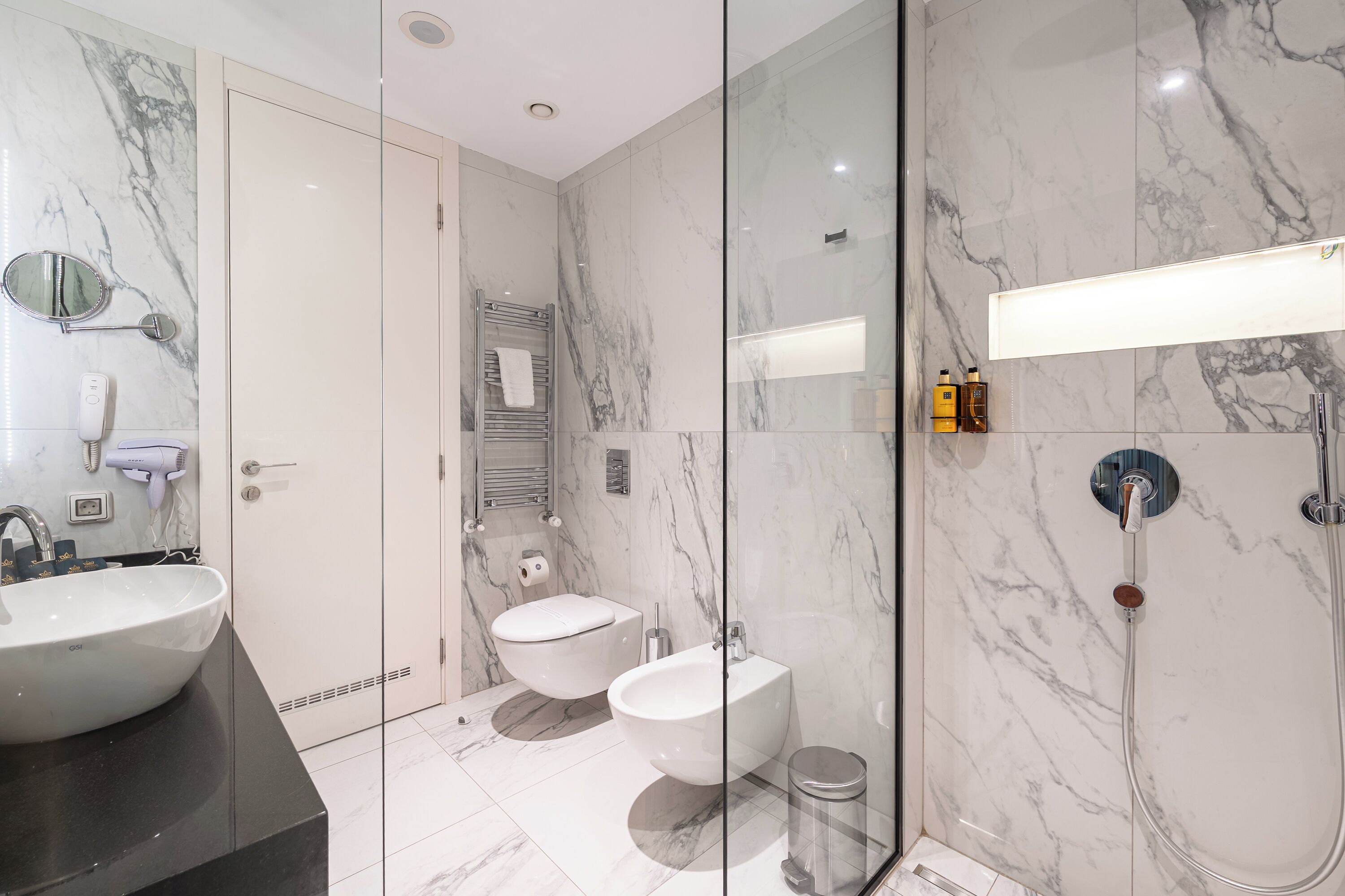 Un baño moderno con un lavamanos grande, bidé y ducha.