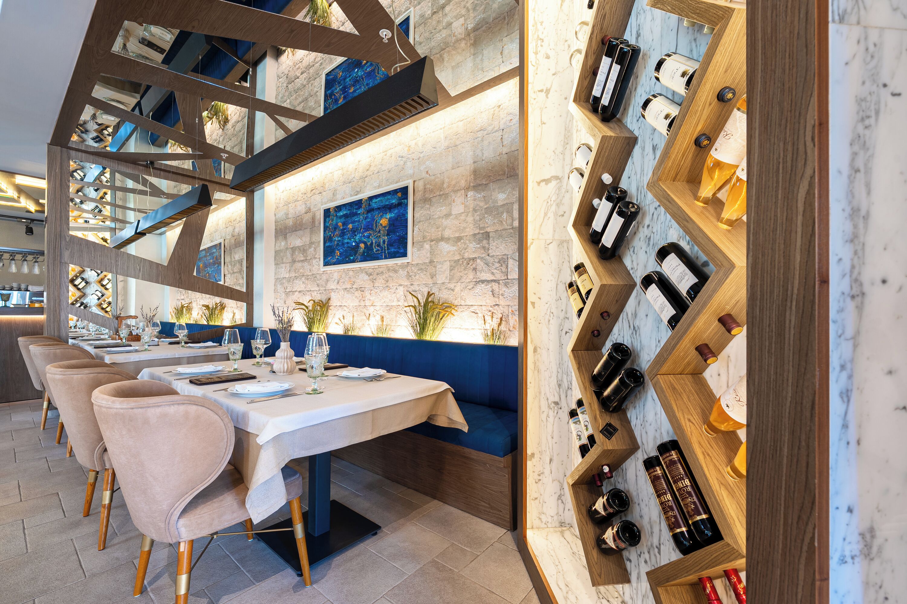 A restaurant with a long table, cushioned seating, and a wine rack.