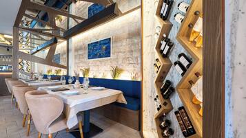 A restaurant with a long table, cushioned seating, and a wine rack.