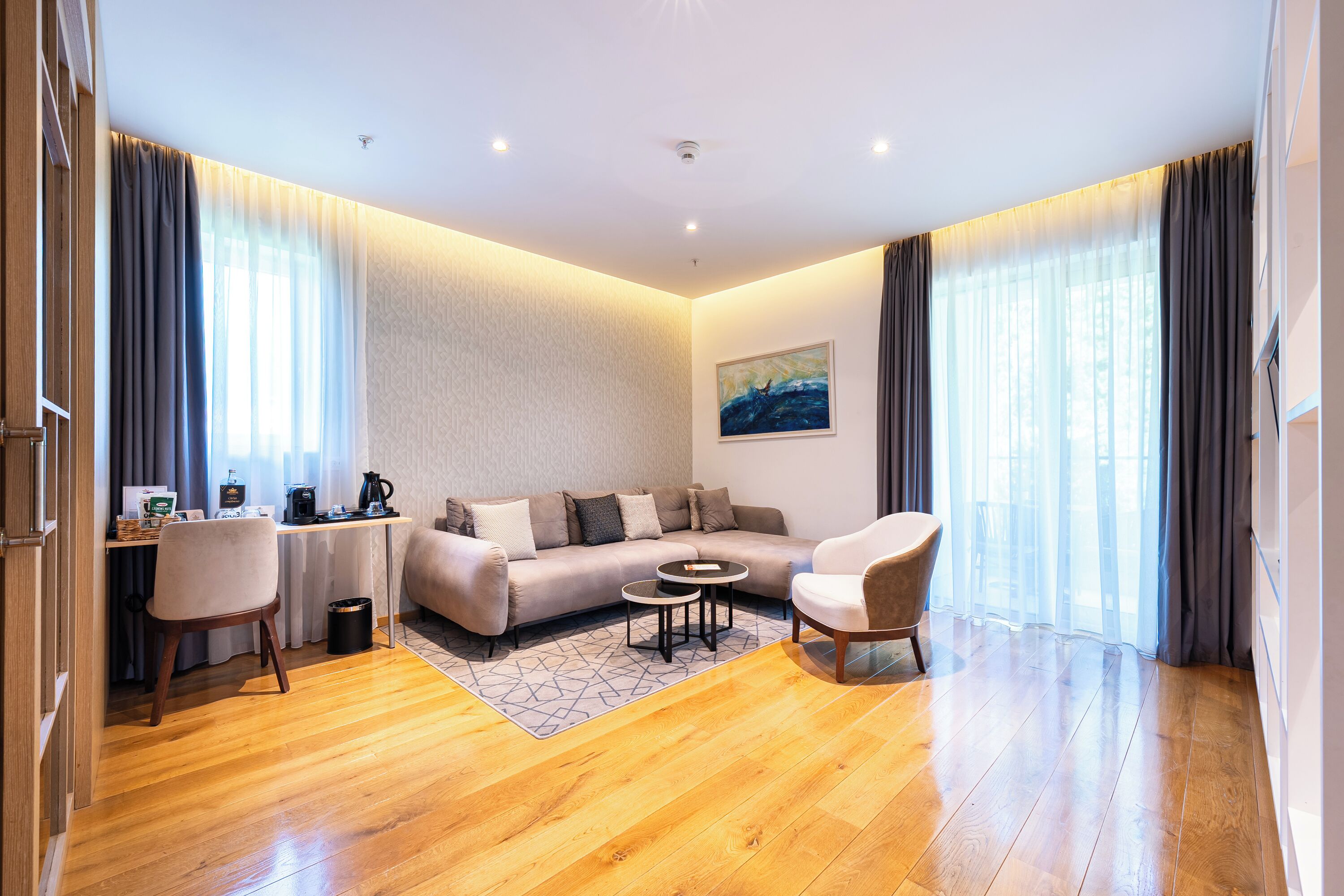 Una sala de estar moderna con un sofá, una mesa de centro, una silla y un escritorio con una computadora y un cafetera.