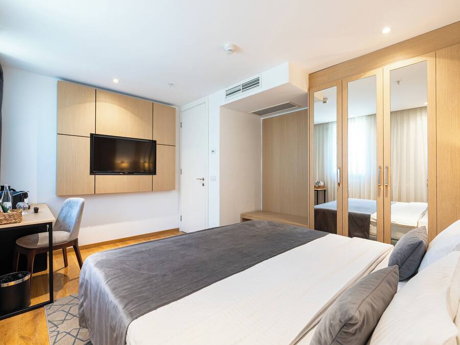 Ein Hotelzimmer mit Bett, Schreibtisch, Stuhl, Fernseher und Kleiderschrank.