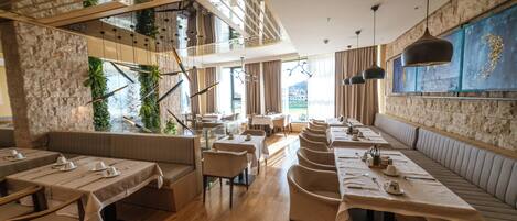 A modern restaurant with wooden flooring, multiple dining areas, and a high ceiling with exposed beams.