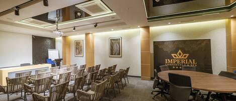 A conference room with a long table, several chairs, a reception desk, and a wall with a logo.