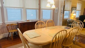 A dining area with a wooden table and chairs, large windows with blinds, and a cozy interior. - 1st-floor, 4-bedroom home, 1 block from beach in Ocean City, NJ (Ocean City)