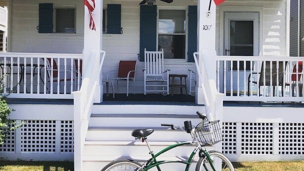 A two-story house with a porch, a bicycle, and American flags. - 1st-floor, 4-bedroom home, 1 block from beach in Ocean City, NJ (Ocean City)