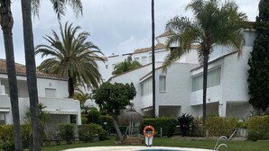 Une piscine équipée d’une bouée de sauvetage, entourée de palmiers et bordée d’un bâtiment blanc.