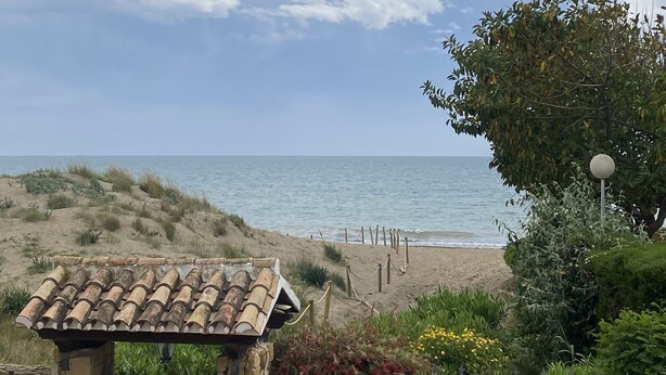 Une vue sur la côte, avec un bâtiment en pierre, une plage et la mer.