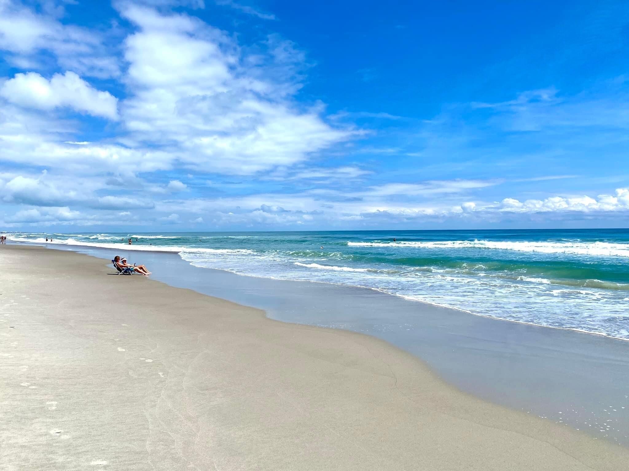 Una playa con cielo despejado y olas.