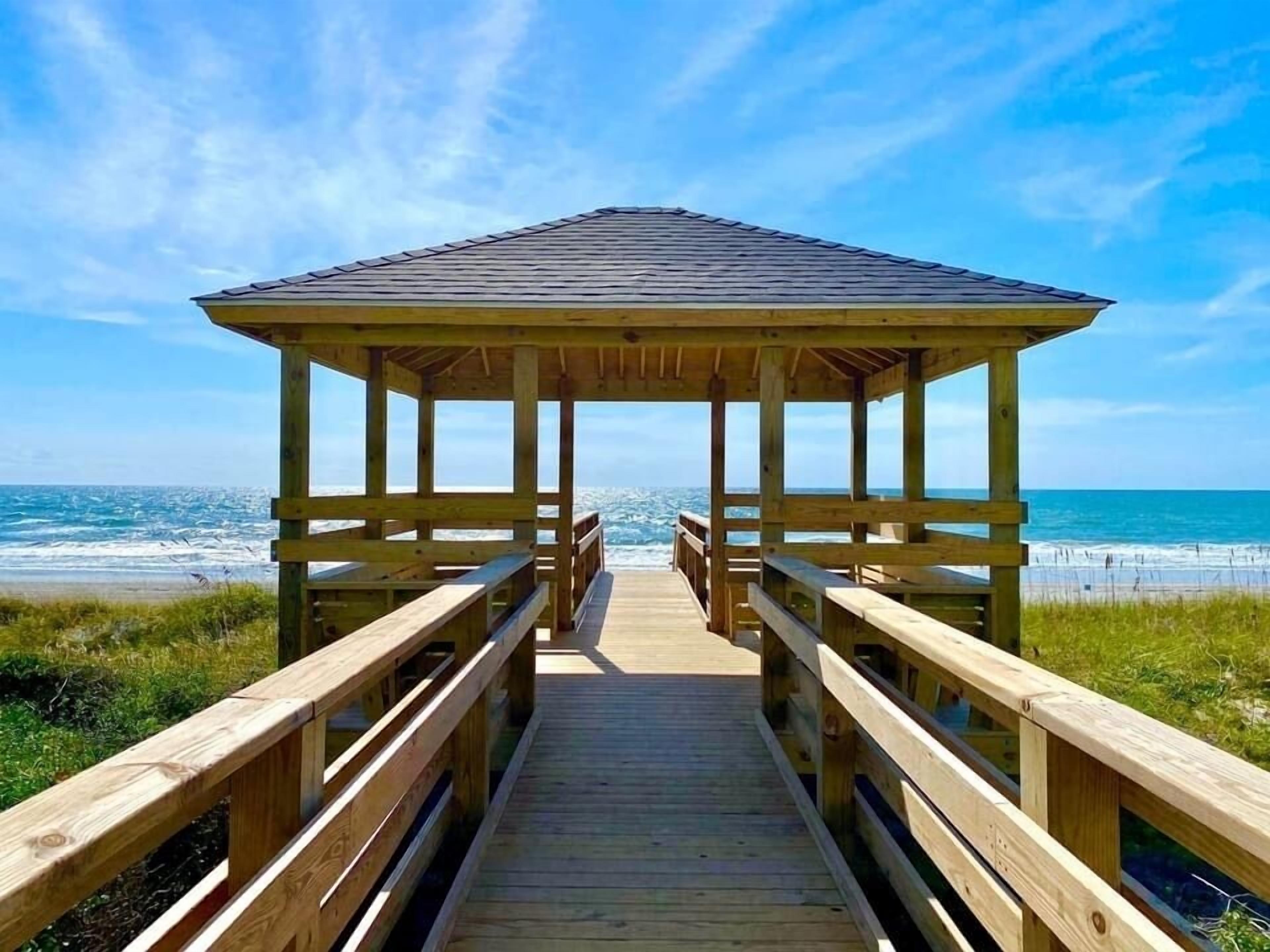 A wooden pier leading to a gazebo with a view of the ocean.