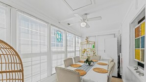 A dining area with a white table, beige chairs, and a ceiling fan. - High Tide in Windy Hill (North Myrtle Beach)