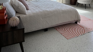 Un dormitorio con cama, mesita de noche, silla, planta en maceta y vista al exterior.