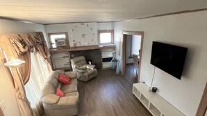 Un grand salon comprenant un canapé, un téléviseur et une cheminée.