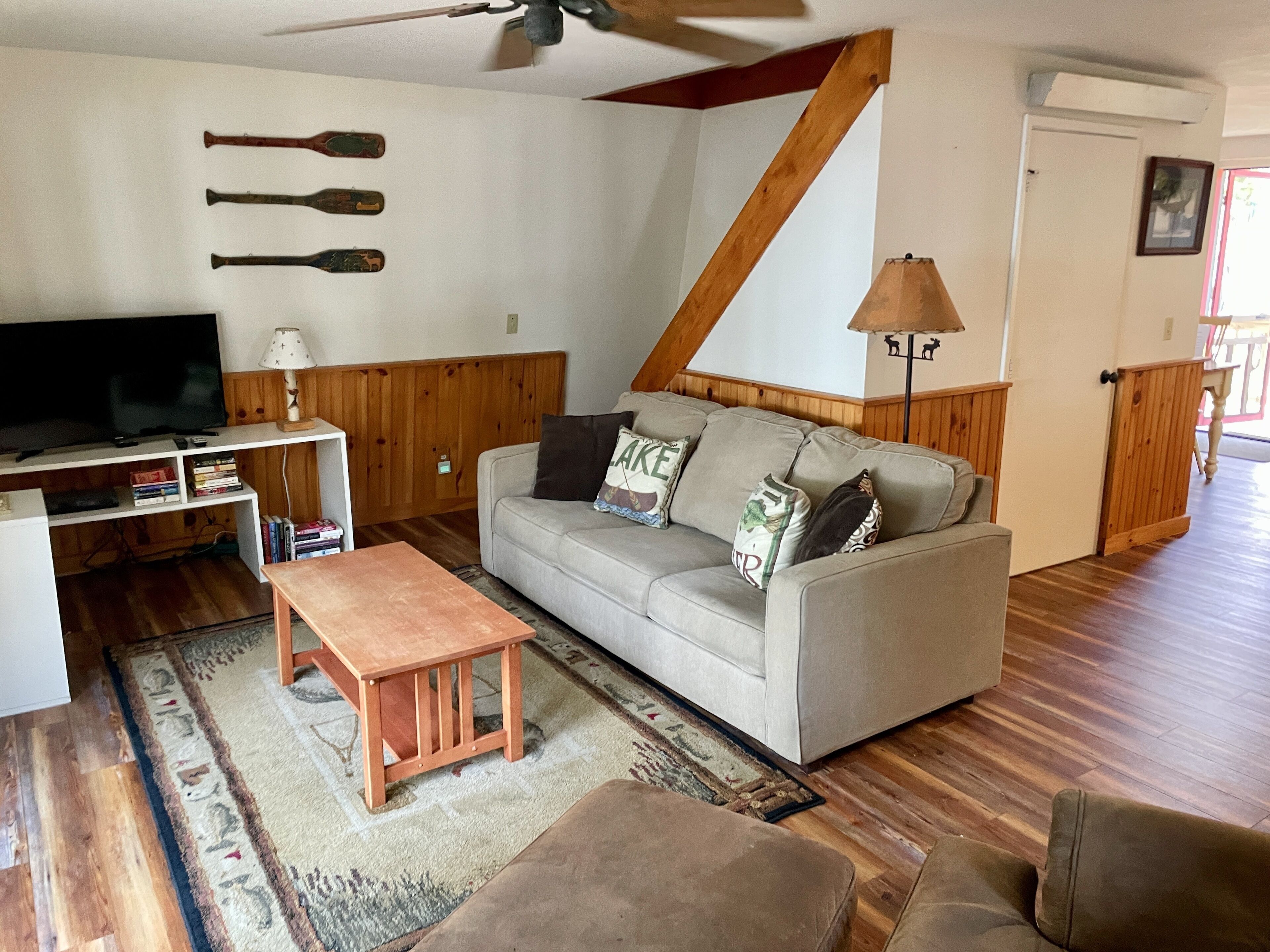 A living room with a sofa, a coffee table, a TV, and a wooden ceiling.