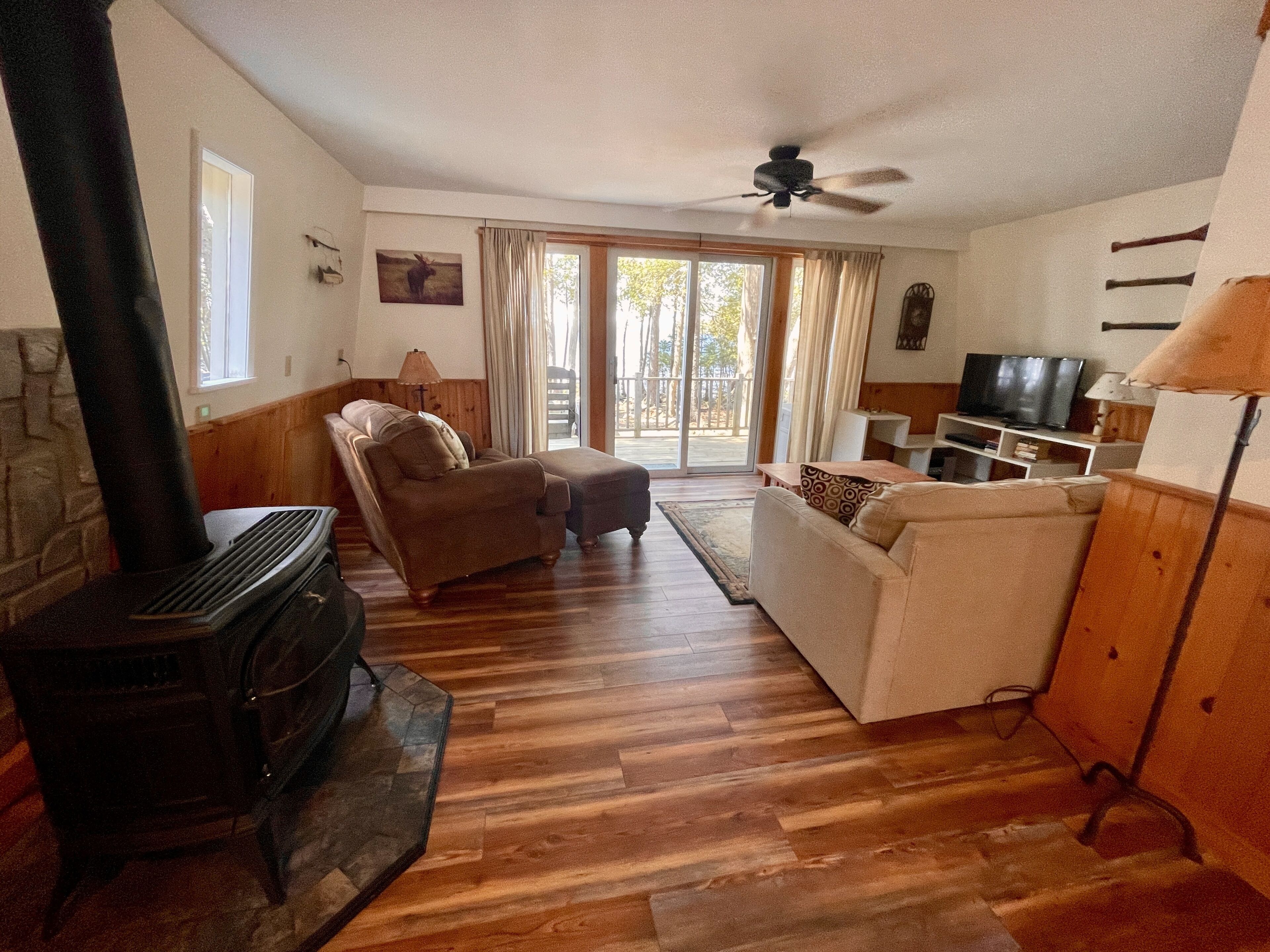 A cozy living room with a fireplace, a sofa, a television, and a ceiling fan.