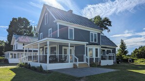 Ein zweigeschossiges Haus mit einer Veranda und einem eingezäunten Garten.