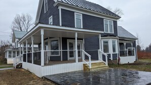 Ein zweistöckiges Haus mit einer Veranda und einem überdachten Eingangsbereich.