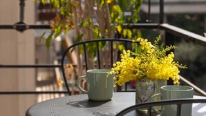 A balcony with a table, chairs, and a vase of yellow flowers. - Urban Athéna Apartment,Pangrati (Athina)