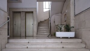 Un escalier en marbre mène à une porte, et un pot de fleurs est placé sur le côté droit.