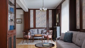 Un salon spacieux comprenant un canapé, deux fauteuils, une table basse et une bibliothèque.