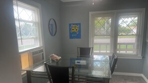 A dining area with a glass table, black chairs, and a painting on the wall.