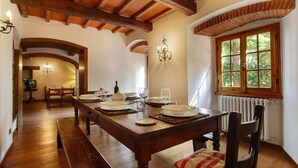 Comedor con mesa de madera dispuesta para cuatro personas, un banco y ventana con vistas a zonas verdes.
