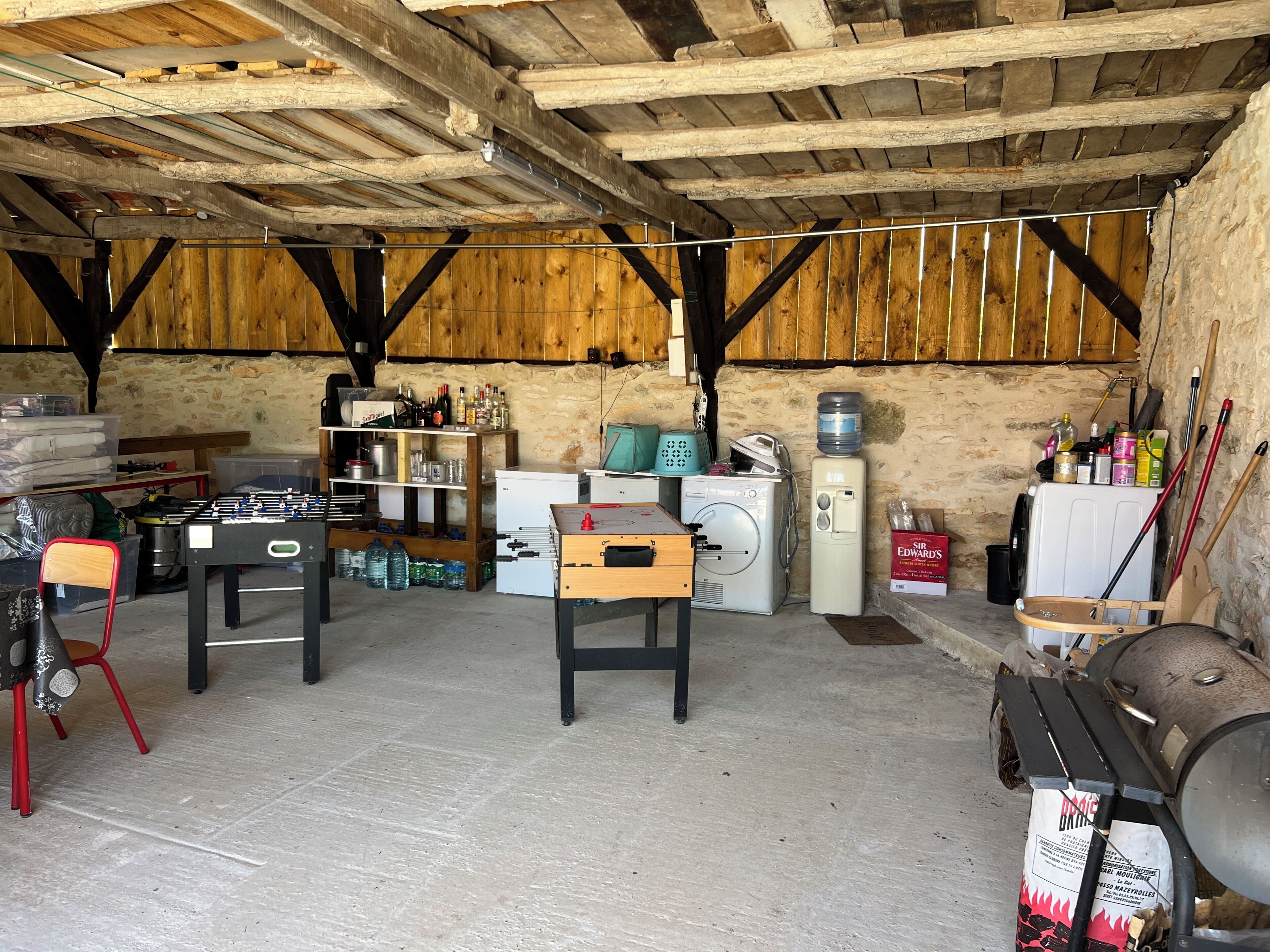 Une pièce rustique avec un plafond en bois, un lave-linge, un chauffe-eau et une table de baby-foot.