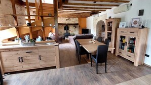 Une cuisine rustique avec des meubles de rangement en bois, une table à manger et un mur en pierre.