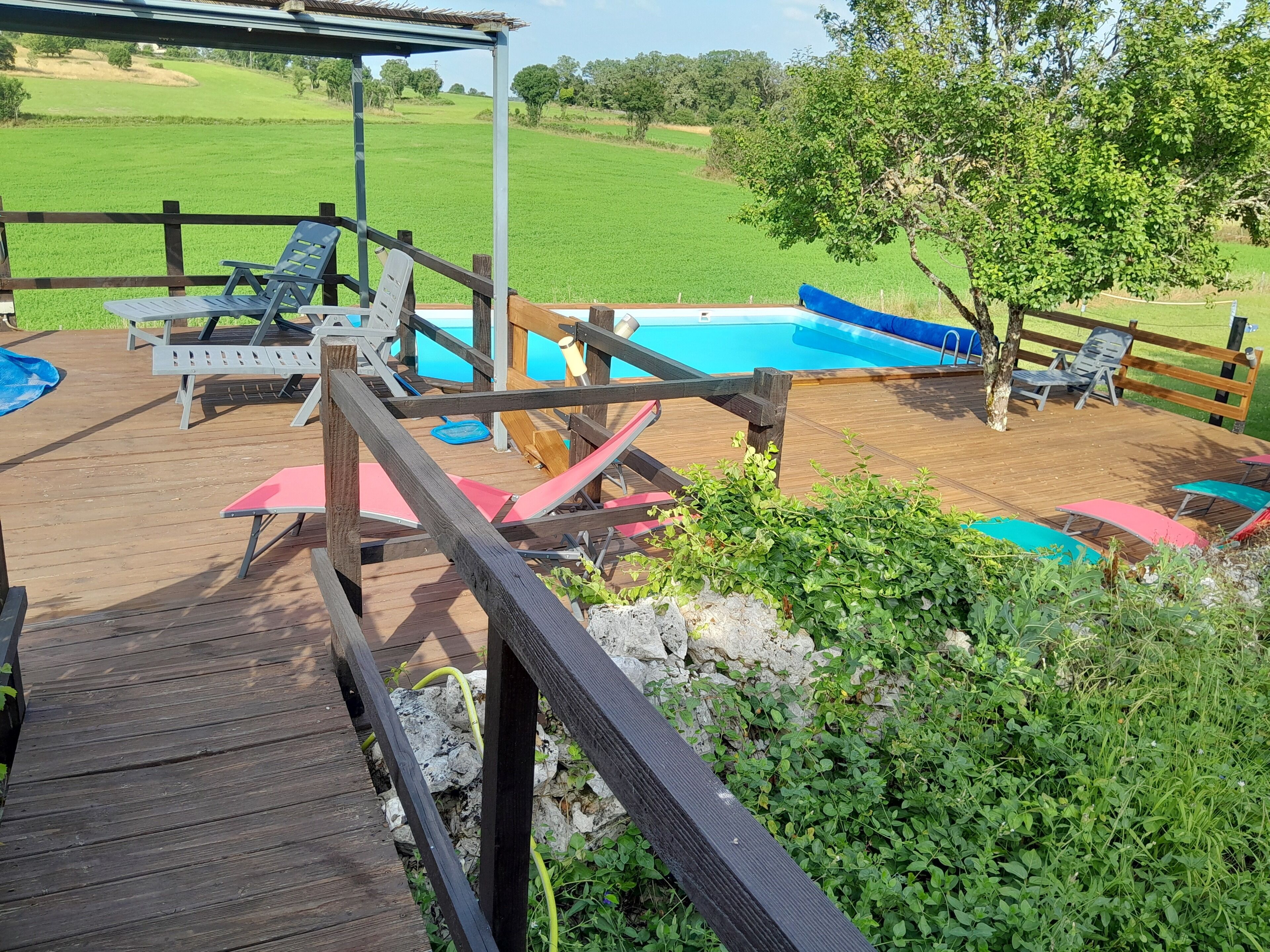 A wooden deck with lounge chairs and a pool area.