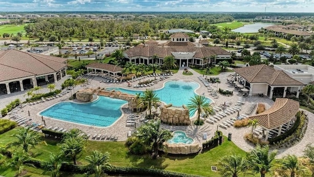 Un resort con una amplia piscina central, varias edificaciones con tejados de cerámica y zonas ajardinadas circundantes.