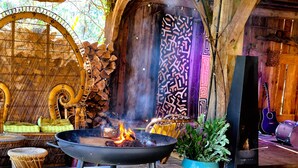 A rustic outdoor seating area with a fire pit, wooden furniture, and decorative elements.