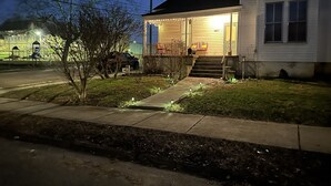 Una casa residencial con porche delantero, escalones y un pequeño jardín.