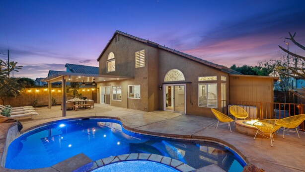 Uma casa com piscina, área de estar externa e um pátio.
