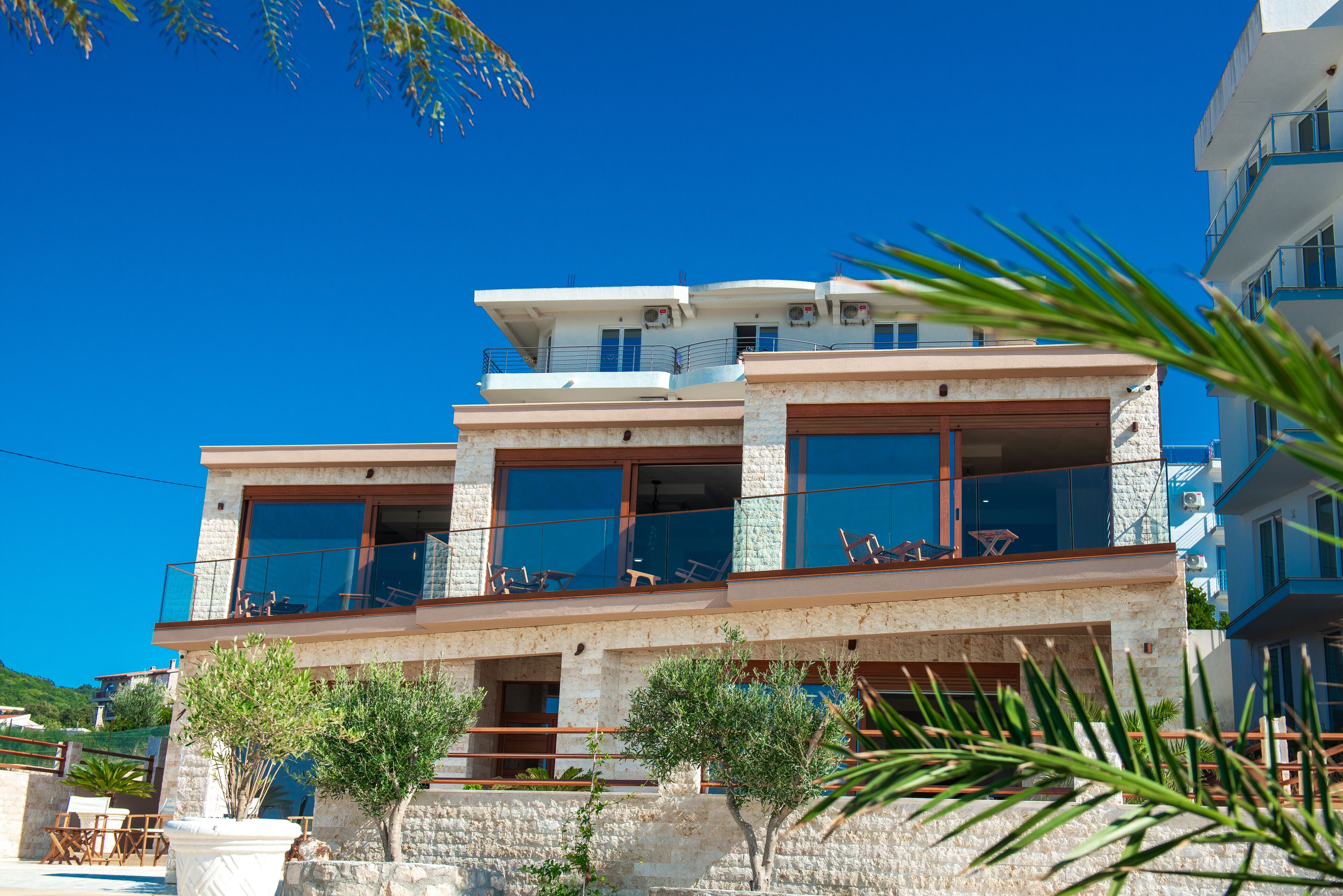 A multi-story building with balconies, large windows, and a stone facade.
