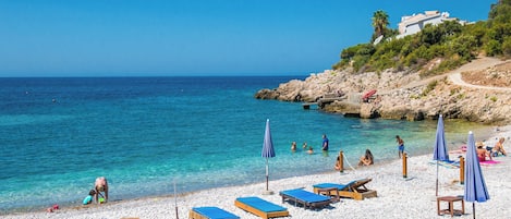 Privatstrand, schwarzer Sandstrand, Liegestühle, Sonnenschirme