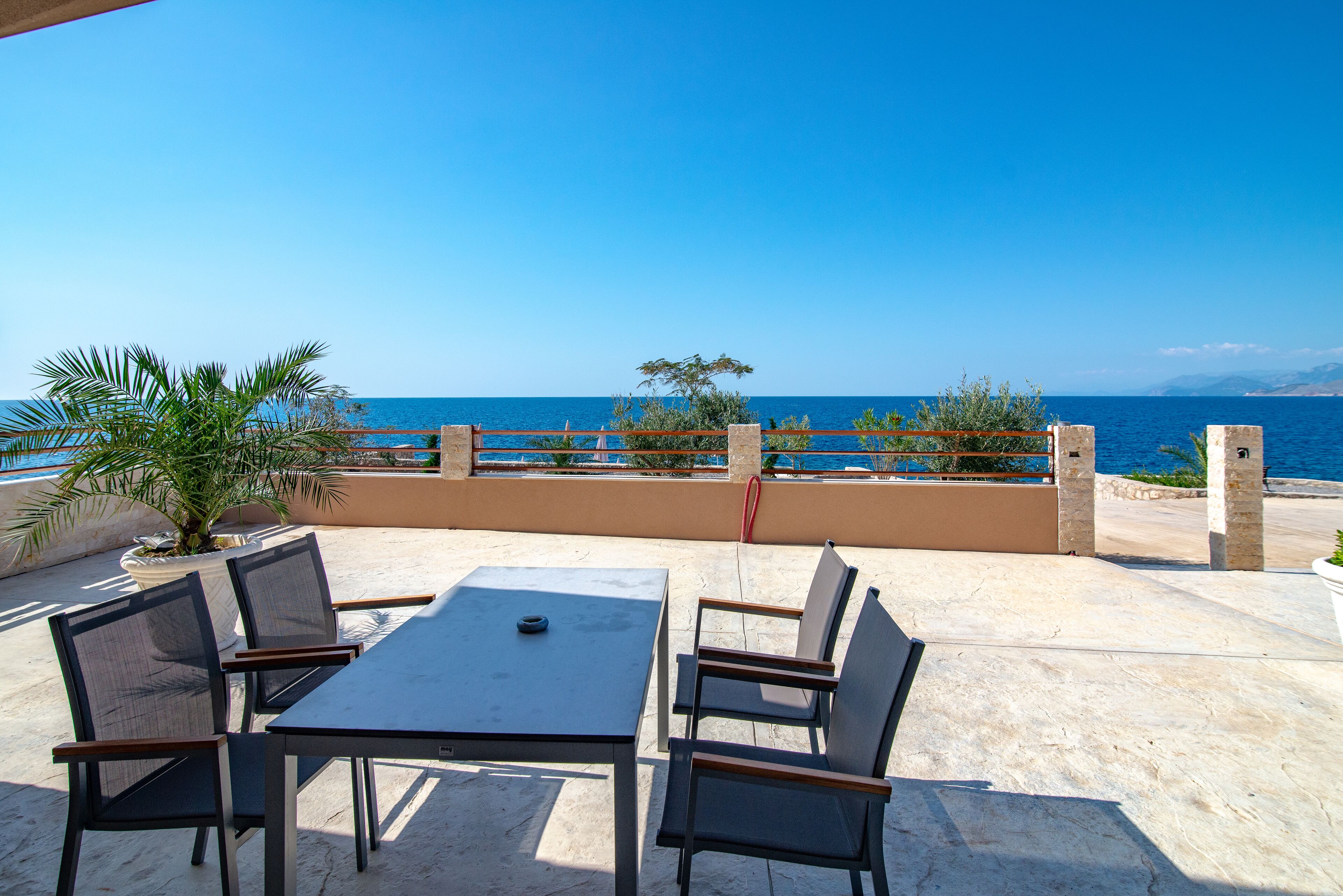 Une terrasse extérieure avec une table et des chaises, offrant une vue sur la côte.