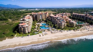 Un complejo turístico con varias edificaciones, un amplio área de piscina y una playa.