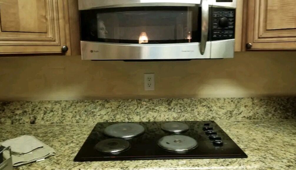 A kitchen with a built-in microwave above a stove with four burners.