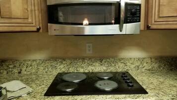 A kitchen with a built-in microwave above a stove with four burners.