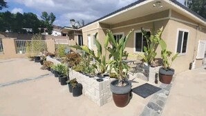 Un edificio residencial con un patio que incluye plantas en macetas y un pequeño espacio con mobiliario exterior.